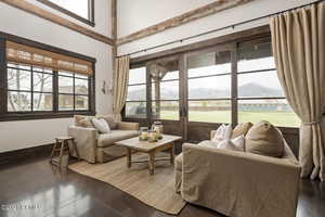 Living area with baseboards, a high ceiling, a mountain view, and concrete flooring