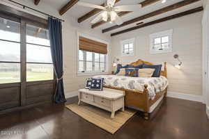 Bedroom featuring baseboards, visible vents, beamed ceiling, wood walls, and concrete floors