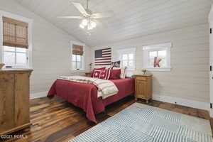 Bedroom featuring baseboards, vaulted ceiling, and dark wood-style flooring