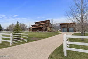 View of front facade featuring an outbuilding, a garage, fence, decorative driveway, and a front yard