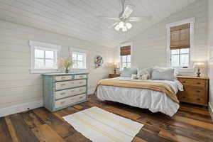 Bedroom with lofted ceiling, dark wood-style flooring, multiple windows, and baseboards