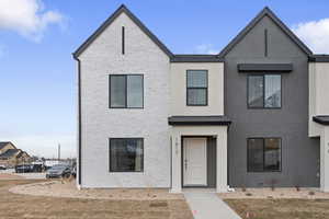 View of front of house featuring brick siding, a front yard, and stucco siding