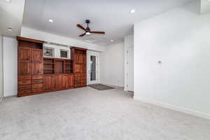 Unfurnished living room featuring light carpet and ceiling fan