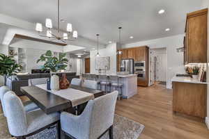 Dining space featuring light hardwood / wood-style flooring, a large fireplace, and a chandelier