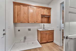 Washroom with cabinets, hookup for a washing machine, light hardwood / wood-style floors, sink, and electric dryer hookup