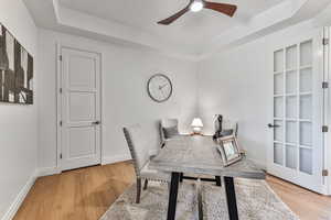 Office featuring a tray ceiling, ceiling fan, and light hardwood / wood-style floors