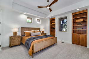 Bedroom featuring ceiling fan, a raised ceiling, and light colored carpet