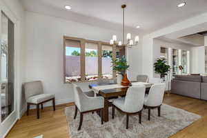 Dining space with light hardwood / wood-style floors and a chandelier