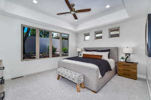 Carpeted bedroom with ceiling fan and a raised ceiling