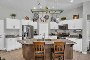 Kitchen with an island with sink, appliances with stainless steel finishes, a breakfast bar, and a sink