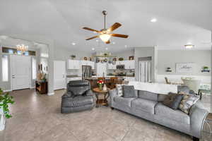 Living room featuring recessed lighting, light tile patterned floors, vaulted ceiling, and ceiling fan with notable chandelier