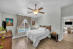 Bedroom with lofted ceiling, visible vents, light wood-style flooring, a ceiling fan, and baseboards