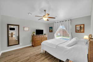 Bedroom with a ceiling fan, wood finished floors, visible vents, and baseboards