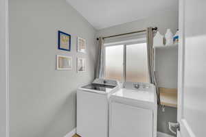 Clothes washing area with washer and dryer, laundry area, and baseboards