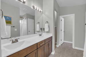 Full bathroom featuring tile patterned floors, a sink, baseboards, and double vanity