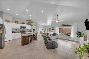 Living area with light tile patterned floors, ceiling fan, and vaulted ceiling