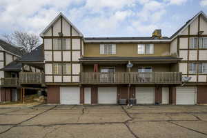 Back of property with a garage, brick siding, and central air condition unit