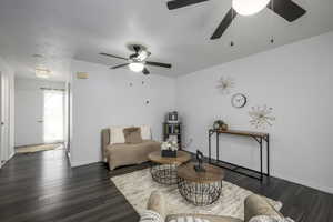 Living area with dark wood finished floors, a ceiling fan, and baseboards