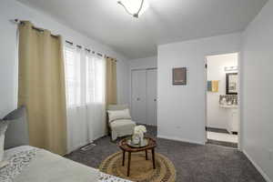 Bedroom featuring dark colored carpet, a closet, visible vents, ensuite bath, and baseboards