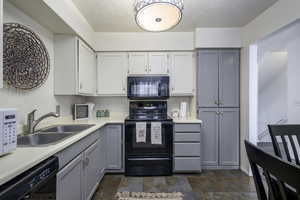 Kitchen featuring black appliances, a sink, light countertops, and gray cabinetry