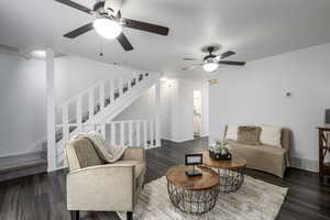 Living room featuring visible vents, stairs, baseboards, and dark wood-style flooring