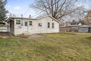 Back of house with fence, a chimney, and a yard