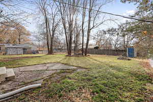 View of yard featuring an outdoor structure, a fenced backyard, and a shed