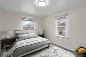 Carpeted bedroom with multiple windows, a textured ceiling, and baseboards