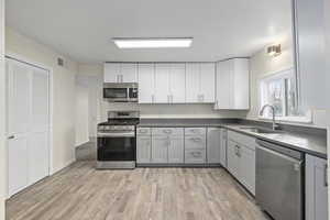 Kitchen featuring a sink, visible vents, appliances with stainless steel finishes, and dark countertops