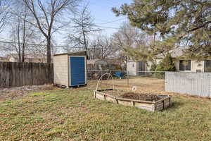 View of yard with a fenced backyard, an outdoor structure, a vegetable garden, and a storage unit