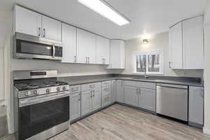 Kitchen featuring dark countertops, white cabinetry, a sink, and appliances with stainless steel finishes