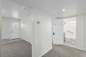 Foyer featuring visible vents, carpet flooring, and a textured ceiling