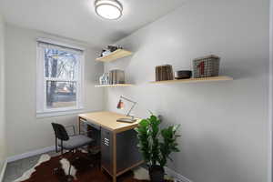 Home office featuring dark colored carpet and baseboards