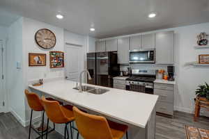 Kitchen with a peninsula, stainless steel appliances, light countertops, a kitchen bar, and a sink