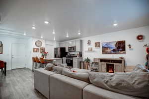 Living room featuring a textured ceiling, baseboards, light wood-style flooring, and recessed lighting