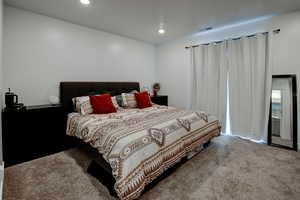 Primary bedroom with carpet, recessed lighting and sliding glass door to balcony