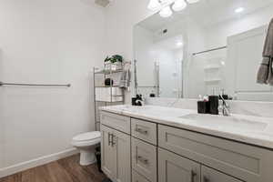 Bathroom featuring hardwood / wood-style flooring, toilet, a shower with door, and vanity