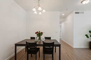 Dining space with light hardwood / wood-style flooring and a chandelier