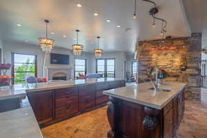 Kitchen with a fireplace, a center island with sink, hanging light fixtures, open floor plan, and a sink