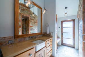 Full bath featuring a stall shower, tasteful backsplash, stone tile flooring, and vanity