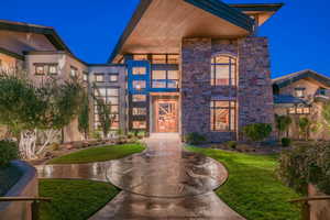 Modern home with stone siding, a front lawn, and stucco siding