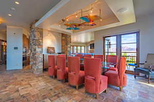 Interior space featuring stone tile flooring, a raised ceiling, and decorative columns