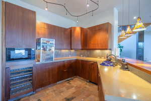 Kitchen with light countertops, modern cabinets, a sink, and pendant lighting