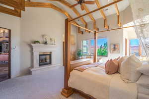 Carpeted bedroom featuring visible vents, a fireplace, high vaulted ceiling, and beamed ceiling