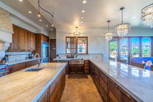 Kitchen with built in refrigerator, a sink, decorative light fixtures, and decorative backsplash