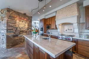 Kitchen with brown cabinetry, a kitchen island with sink, and a sink