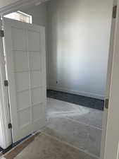 Spare room featuring unfinished concrete floors and baseboards