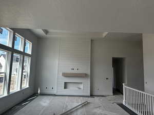 Unfurnished living room with plenty of natural light, a textured ceiling, baseboards, and visible vents