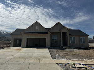 Unfinished property featuring driveway, board and batten siding, and a garage