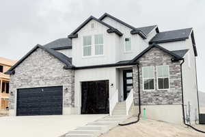 Modern farmhouse style home with concrete driveway, board and batten siding, an attached garage, and roof with shingles